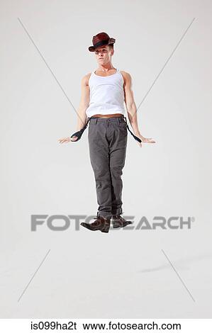 Stock Photograph - Dancer jumping in the air while holding trouser braces. Fotosearch