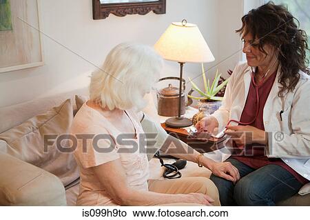 Doctor taking senior woman's blood pressure View Large Photo Image Picture - Doctor taking senior woman's blood pressure. Fotosearch