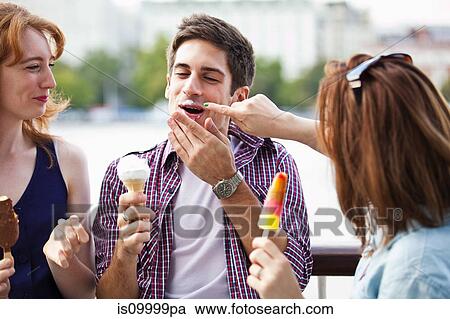 Stock Image - Friends eating icecreams and lollypops. Fotosearch