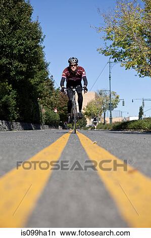 Picture - Man cycling between double yellow lines. Fotosearch