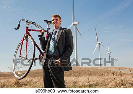 Man holding bicycle in front of wind turbines View Large Photo Image Stock Image - Man holding bicycle in front of wind turbines. Fotosearch