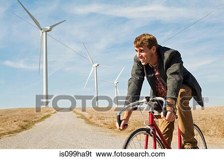 Man on bicycle in front of wind turbines View Large Photo Image Stock Photograph - Man on bicycle in front of wind turbines. Fotosearch