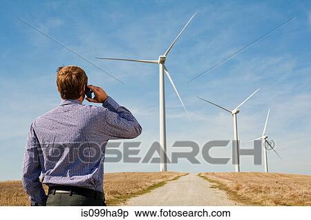 Man on mobile phone watching wind turbines View Large Photo Image Stock Photography - Man on mobile phone watching wind turbines. Fotosearch