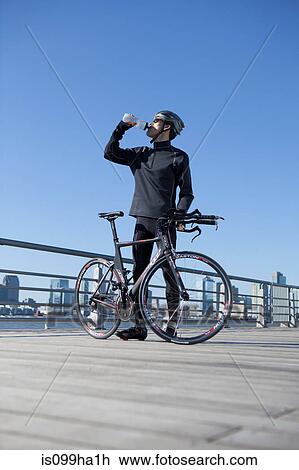 Man quenching thirst behind his racing bike View Large Photo Image Stock Image - Man quenching thirst behind his racing bike. Fotosearch