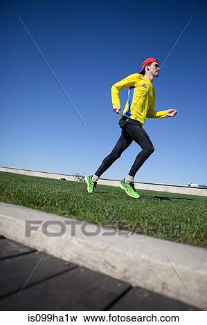 Man running on grass verge View Large Photo Image Stock Photo - Man running on grass verge. Fotosearch