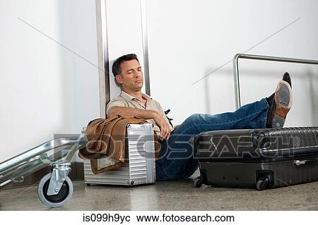 Man sleeping on luggage in airport View Large Photo Image Stock Image - Man sleeping on luggage in airport. Fotosearch