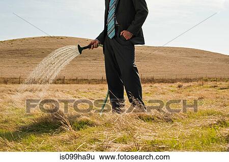 Man sprinkling water on dry grass View Large Photo Image Stock Photograph - Man sprinkling water on dry grass. Fotosearch