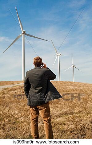 Man standing in front of wind turbines on mobile phone View Large Photo Image Stock Photography - Man standing in front of wind turbines on mobile phone. Fotosearch