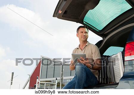 Stock Photo - Man using data tablet in airport carpark. Fotosearch