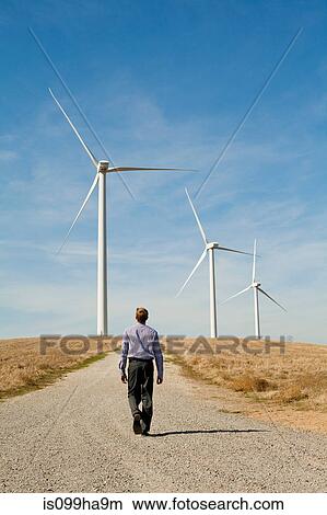 Man walking towards wind turbines View Large Photo Image Picture - Man walking towards wind turbines. Fotosearch