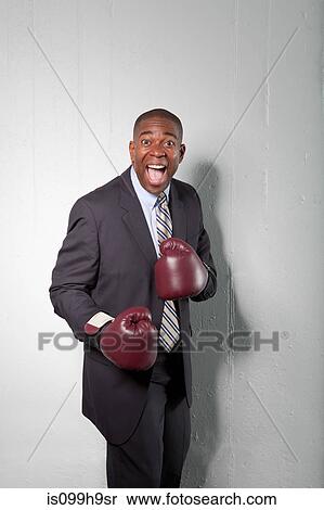 Mature businessman wearing boxing gloves, smiling View Large Photo Image Stock Photography - Mature businessman wearing boxing gloves, smiling. Fotosearch