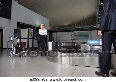 Mid adult businesswoman waiting for luggage in airport baggage re-claim View Large Photo Image Stock Photograph - Mid adult businesswoman waiting for luggage in airport baggage re-claim. Fotosearch