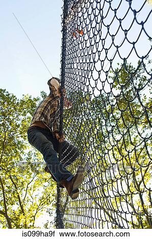 Mid adult man climbing over chain link fence View Large Photo Image Stock Image - Mid adult man climbing over chain link fence. Fotosearch