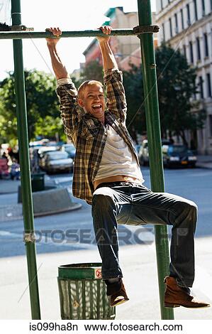 Mid adult man hanging from street lamp post View Large Photo Image Picture - Mid adult man hanging from street lamp post. Fotosearch