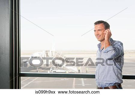 Mid adult man on the phone at airport viewing platform View Large Photo Image Stock Photo - Mid adult man on the phone at airport viewing platform. Fotosearch