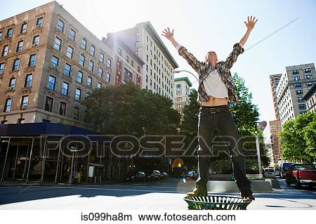 Mid adult man standing on litter bin in city View Large Photo Image Picture - Mid adult man standing on litter bin in city. Fotosearch