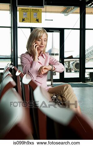 Mid adult woman on the phone in airport departure lounge View Large Photo Image Stock Photograph - Mid adult woman on the phone in airport departure lounge. Fotosearch