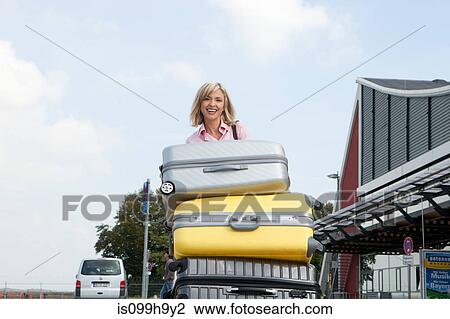 Mid adult woman pushing luggage trolley to airport View Large Photo Image Stock Image - Mid adult woman pushing luggage trolley to airport. Fotosearch