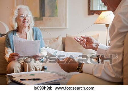 Stock Image - Senior couple discussing paperwork at home. Fotosearch
