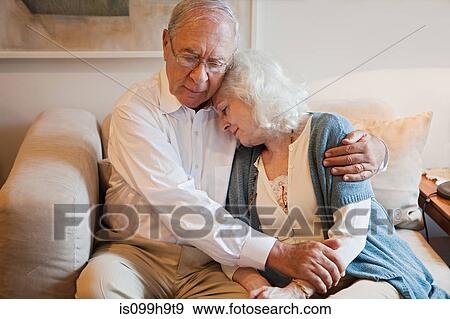 Senior couple embracing on sofa at home View Large Photo Image Stock Photo - Senior couple embracing on sofa at home. Fotosearch