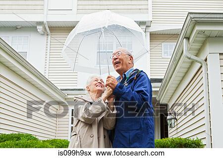 Senior couple holding umbrella outside View Large Photo Image Stock Photo - Senior couple holding umbrella outside. Fotosearch