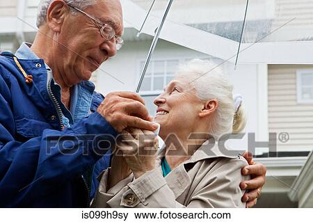 Senior couple holding umbrella outside View Large Photo Image Stock Photo - Senior couple holding umbrella outside. Fotosearch