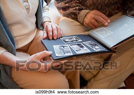 Picture - Senior couple looking through photo album, mid section. Fotosearch