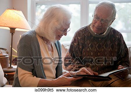 Stock Photography - Senior couple looking through photo album. Fotosearch