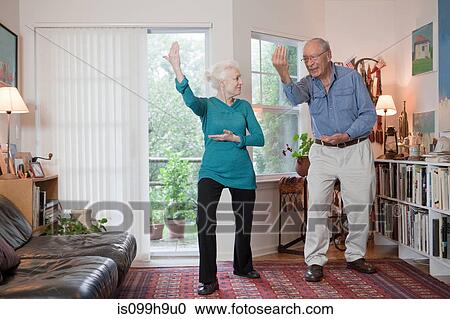 Stock Image - Senior couple performing tai chi in living room. Fotosearch