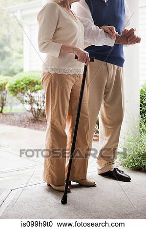 Stock Image - Senior couple standing with walking stick. Fotosearch
