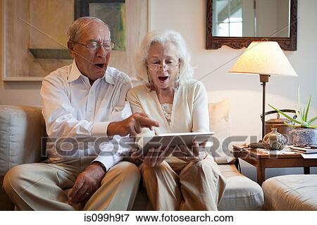 Stock Photo - Senior couple using computer tablet at home. Fotosearch
