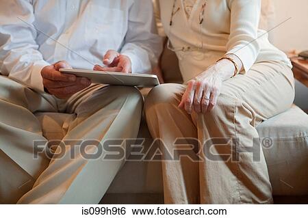 Senior couple using computer tablet at home, mid section View Large Photo Image Stock Photograph - Senior couple using computer tablet at home, mid section. Fotosearch