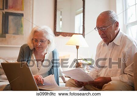 Stock Image - Senior couple using latop in home. Fotosearch
