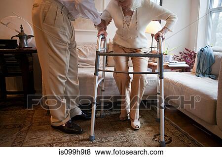 Senior man assisting wife with walking frame at home View Large Photo Image Stock Photo - Senior man assisting wife with walking frame at home. Fotosearch