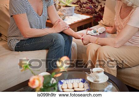 Senior woman and daughter holding hands on sofa View Large Photo Image Stock Photography - Senior woman and daughter holding hands on sofa. Fotosearch