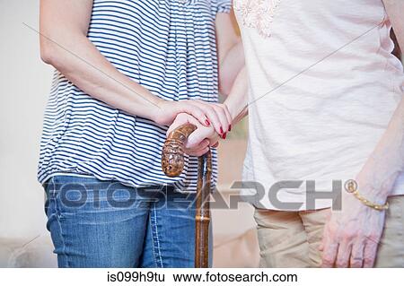 Stock Photograph - Senior woman and daughter holding walking stick. Fotosearch
