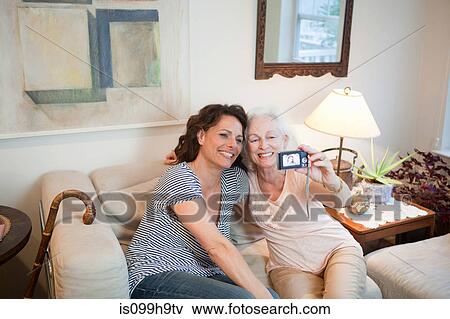Senior woman and daughter taking self portrait in home View Large Photo Image Stock Photo - Senior woman and daughter taking self portrait in home. Fotosearch