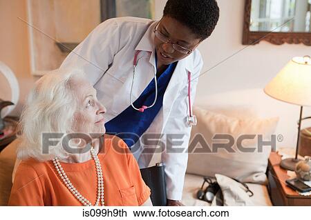 Stock Image - Senior woman and doctor in home. Fotosearch