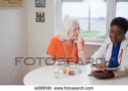 Senior woman and doctor using computer tablet at table View Large Photo Image Stock Image - Senior woman and doctor using computer tablet at table. Fotosearch