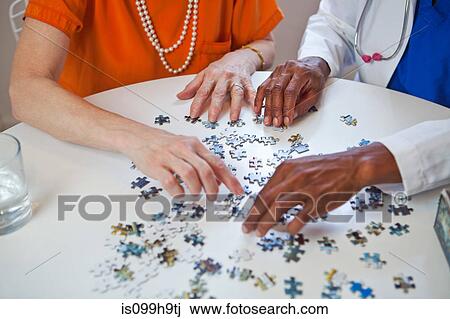 Stock Image - Senior woman and doctor with jigsaw puzzle. Fotosearch