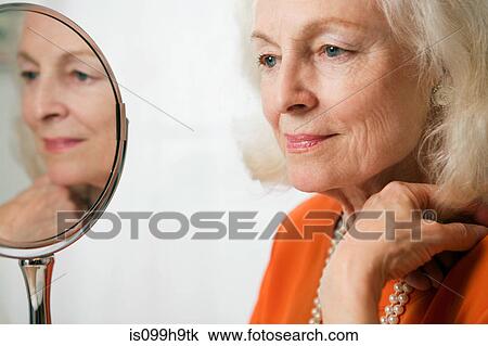 Stock Image - Senior woman with reflection in mirror. Fotosearch