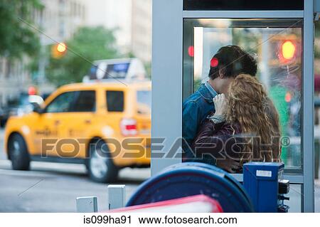 Stock Image - Young couple kissing in telephone booth. Fotosearch