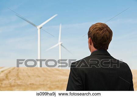Young man watching wind turbines View Large Photo Image Stock Image - Young man watching wind turbines. Fotosearch