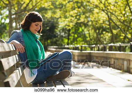 Stock Photograph - Young woman reading in park. Fotosearch