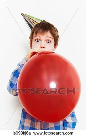 Stock Image - Boy blowing up balloon. Fotosearch