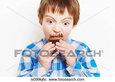 Stock Image - Boy devouring a cupcake. Fotosearch