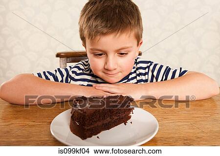 Picture - Boy looking at slice of chocolate cake. Fotosearch