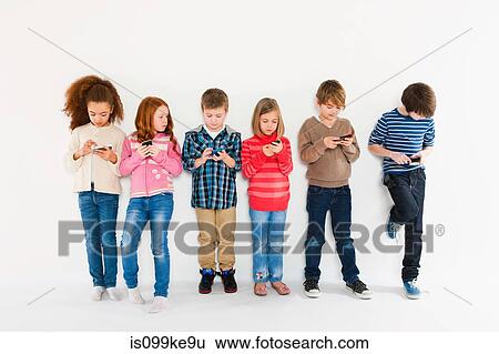 Children using smartphones, standing in a row View Large Photo Image Stock Photograph - Children using smartphones, standing in a row. Fotosearch