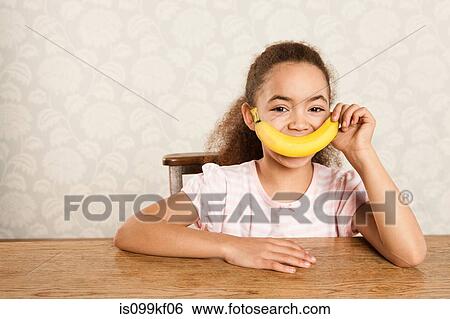 Stock Photograph - Girl holding a banana over her mouth. Fotosearch