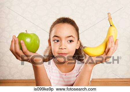 Girl holding apple and banana View Large Photo Image Stock Photography - Girl holding apple and banana. Fotosearch